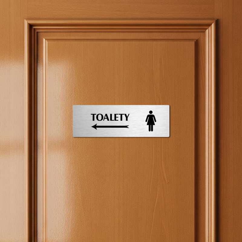 Toalety vlevo ženy, 240x79mm, zlatá popiska s okrasným rámečkem  